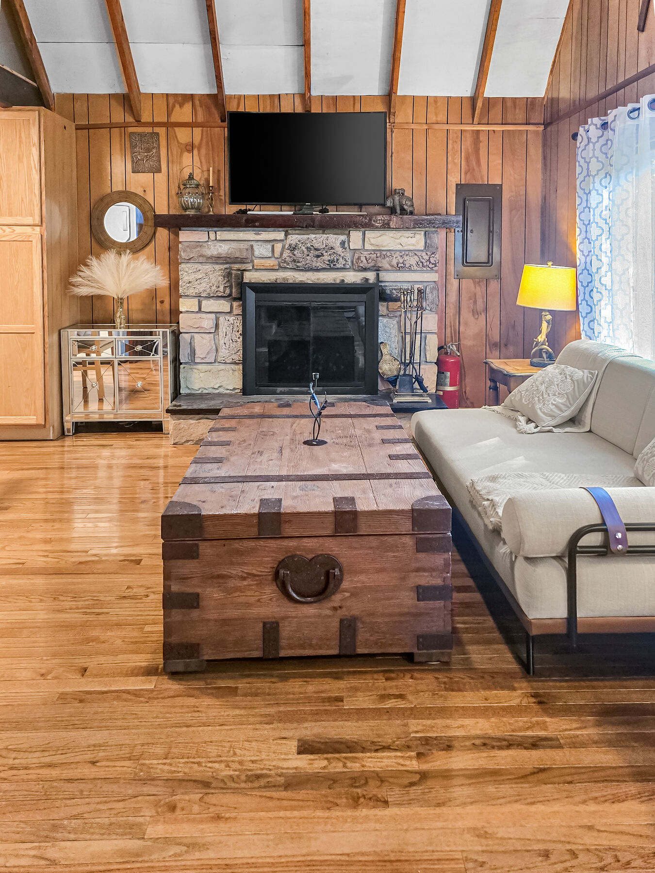 Living room with stone fireplace and vaulted wood ceiling